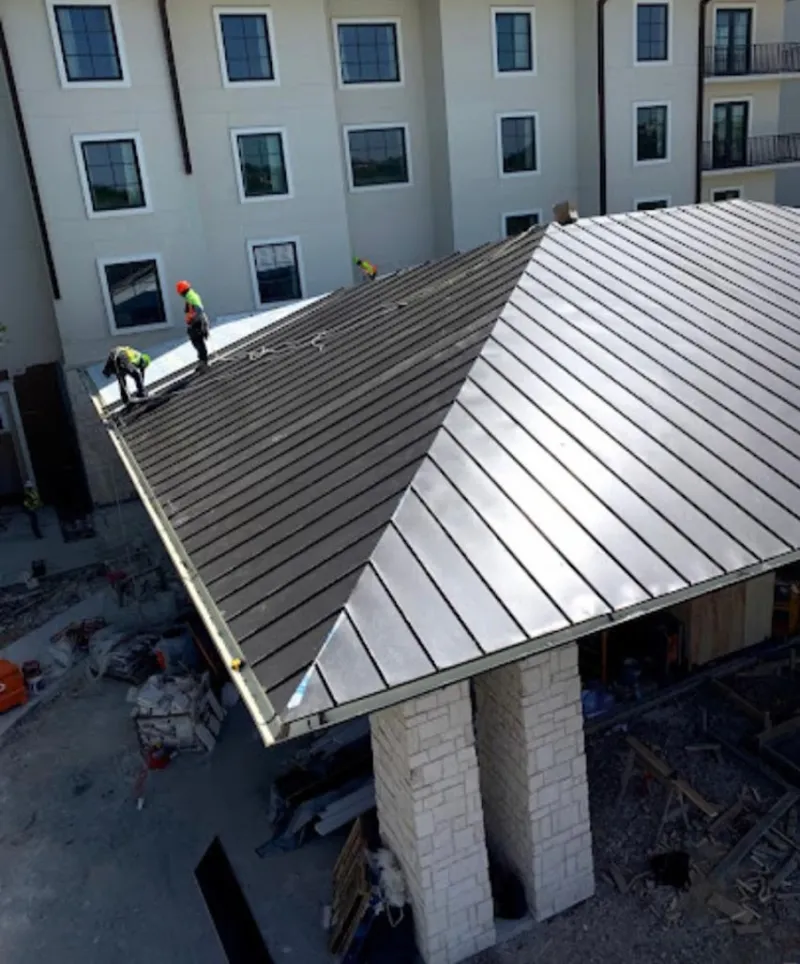 Crew installing standing seam metal roof panels on a commercial project in Clearfield